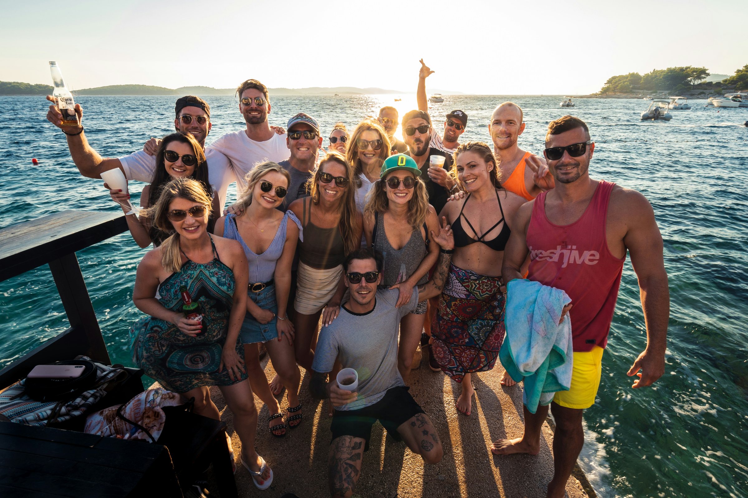Group of friends celebrating together on a dock at golden hour on the coast